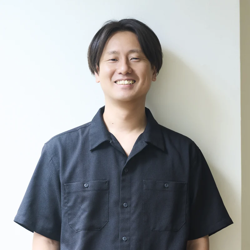 白い壁の前で、ポケットに手を入れて笑うD・O