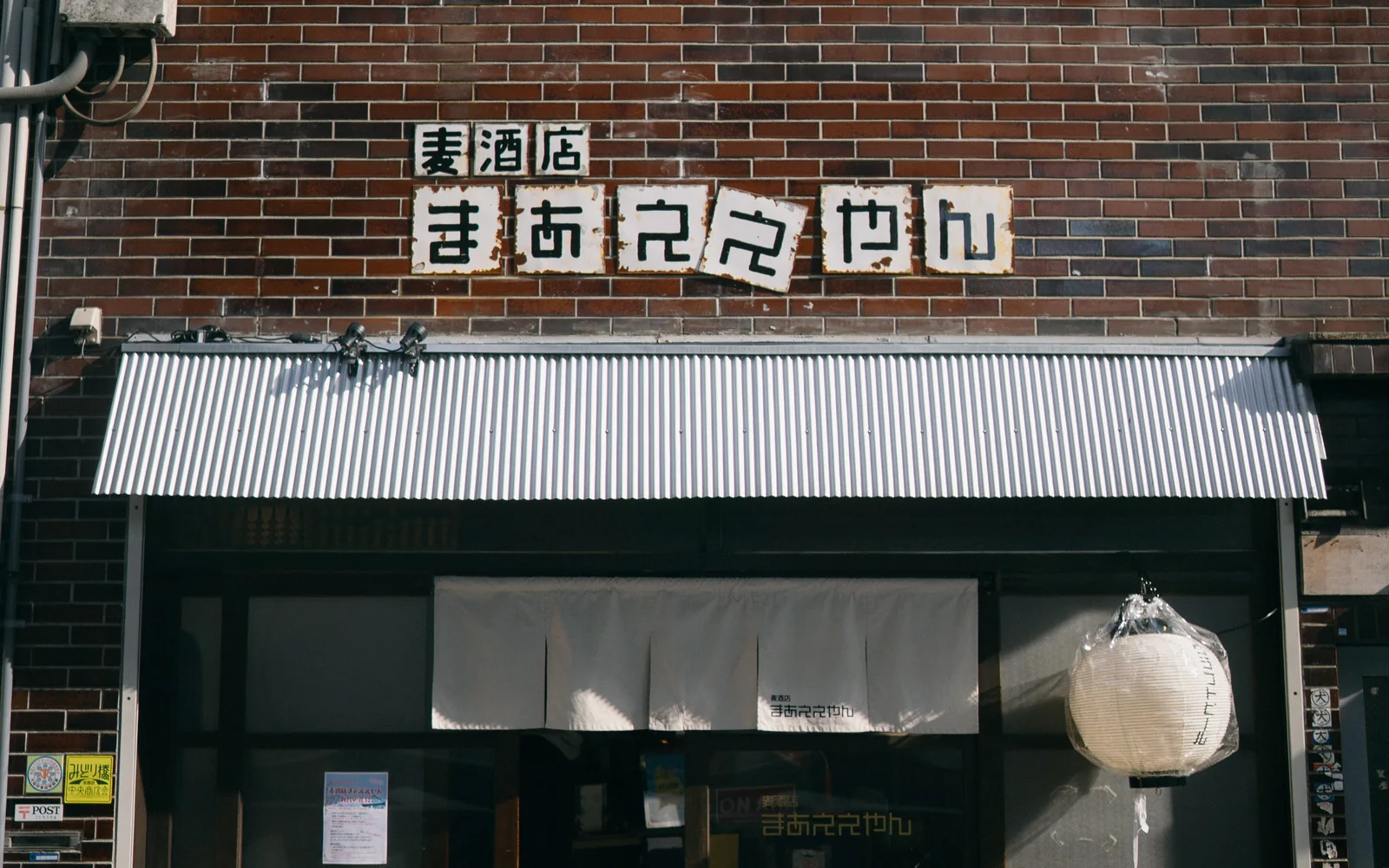 緑橋オフィスの外観。1階に「麦酒店まぁええやん」の看板とのれん