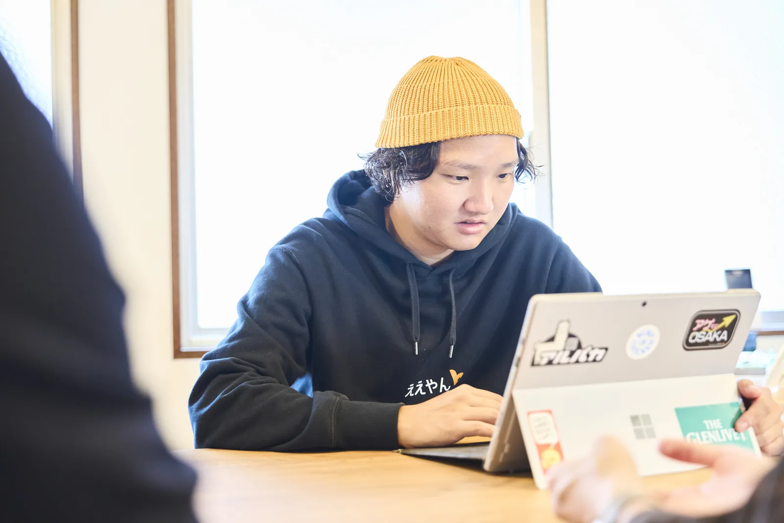 打ち合わせで、話を聞きながらパソコンにメモをとるスタッフ