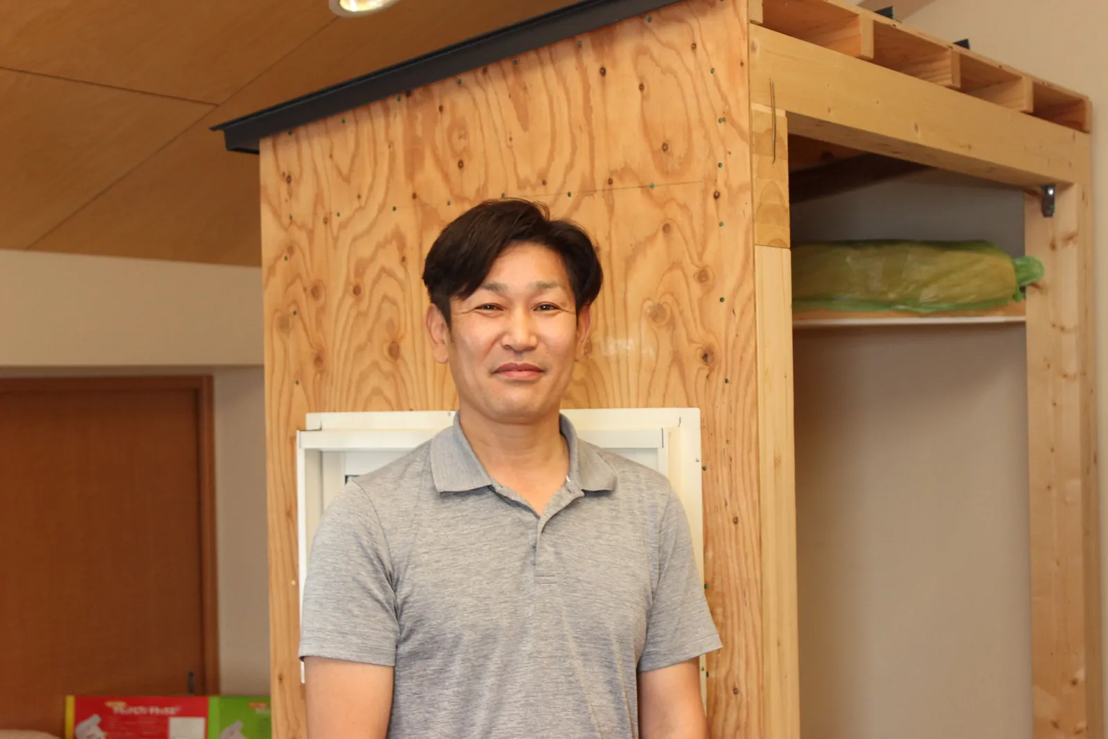木の骨組みの前に立つ中澤社長