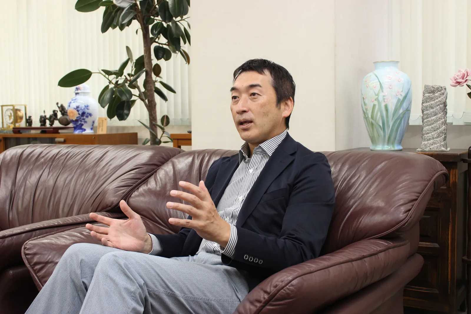 ソファで身ぶりを交えて話す俣野社長