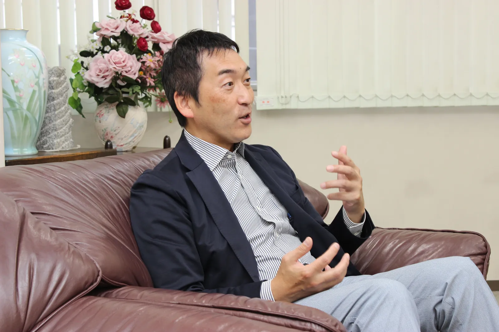 花の飾られた応接室で話す俣野社長