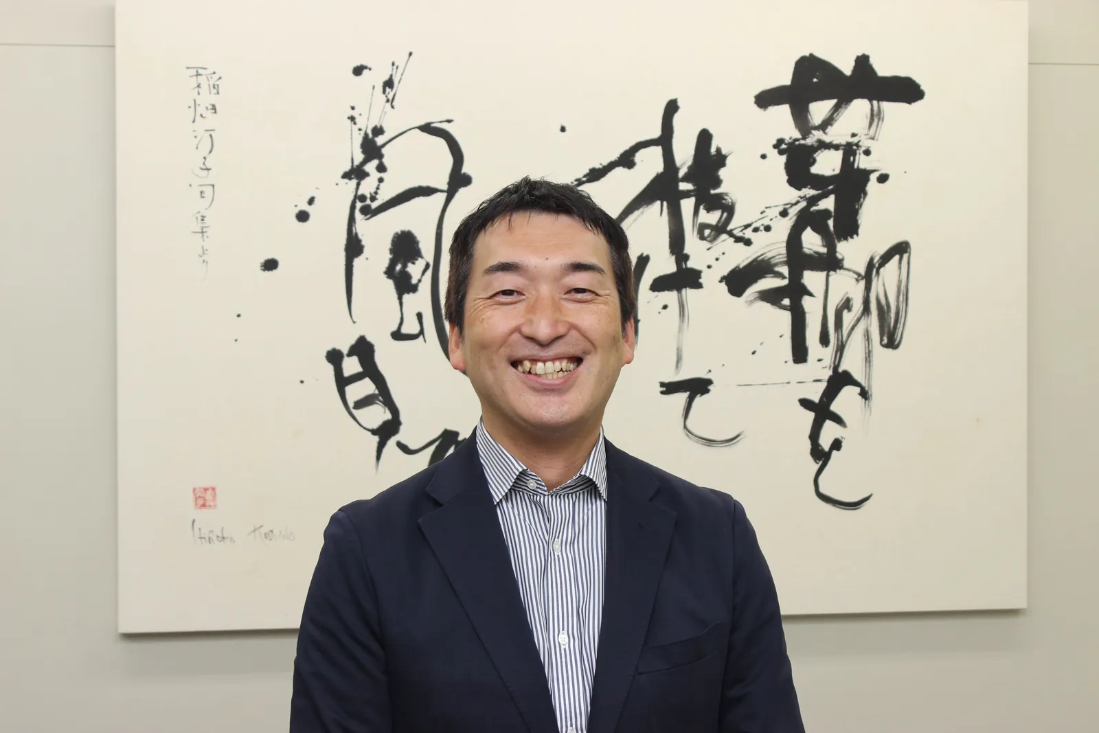 書の前で笑う俣野社長